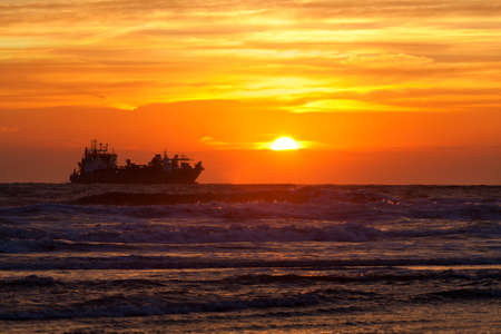 ship silhouette on North sea at sunset, Netherlandsの写真素材