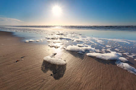 sunshine over North sea waves on beach, Netherlandsの写真素材