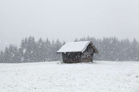heavy snowstorm over old wooden hut, Bavaria, Germanyの写真素材
