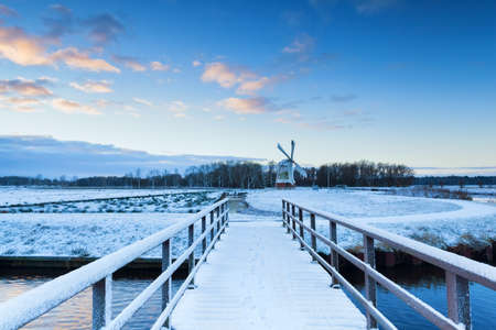 bridge to windmill in snowy winter, Netherlandsの写真素材