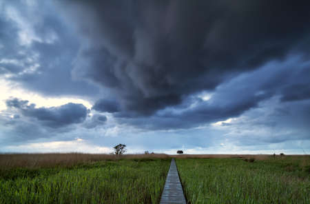 dramatic stormy clouds over pier path on coastの写真素材