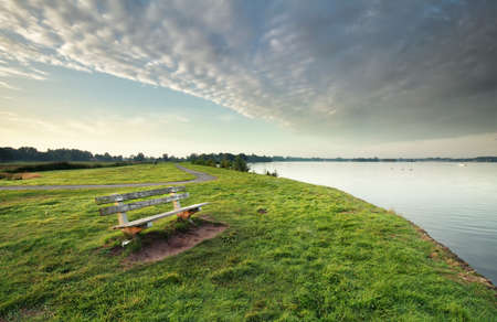 bench on green grass by big lake and bike roadの写真素材