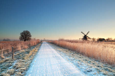 cycling road and windmill in Dutch countryside during winterの写真素材