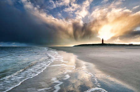 dramatic sunrise sky over lighthouse on beachの写真素材
