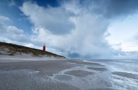 windy stormy morning on north sea coast with red lighthouseの写真素材