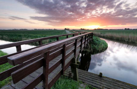 wooden bridge for bicycles via river at sunrise, Hollandの写真素材