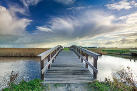 wooden bridge via river and blue sky, Netherlandsの写真素材