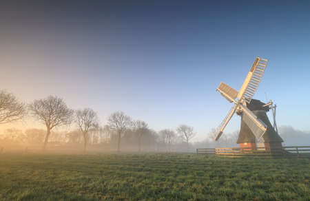 Dutch windmill in misty sunrise during summer