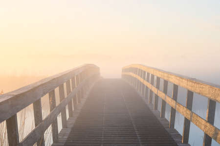wooden bridge in dense fog at sunriseの写真素材