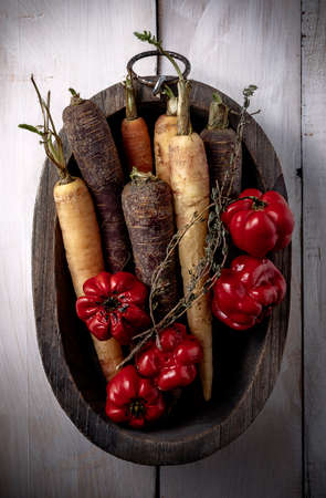raw carrots and peppers in wooden bowl on table