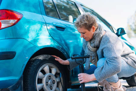 adult woman in the foreground inflating car tyreの写真素材