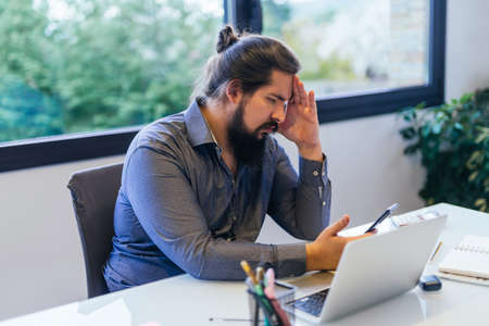 Young businessman worried while looking at his mobile phoneの写真素材