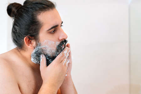 young man with bushy beard, spreading shaving foam.の写真素材