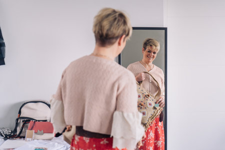 mature woman enjoying a shopping day. blonde female woman testing a handbags in front of a mirror. shopping concept.の写真素材