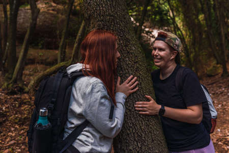 two young women looking at each other romantically in the shade of a tree. young people on vacation.の写真素材