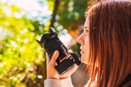young woman amateur photographer, taking pictures of a mountain landscape. young redhead...