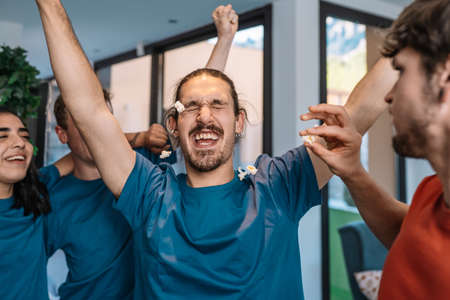 group of friends jumping for joy after the victory of their soccer team. losing team throws popcorn...