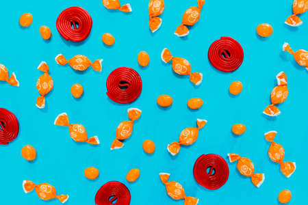 Candy, orange candies and red swirls on blue background. assortment of candies. wallpaper to use text.の写真素材