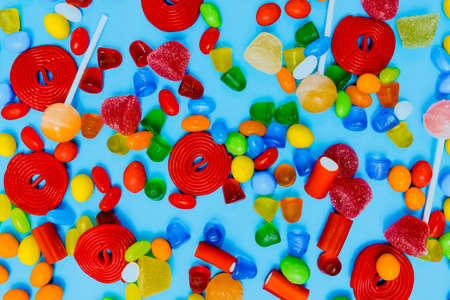 Assorted gummy candies in different colours and shapes on a blue background. Top view. Assorted gummy candiesの写真素材