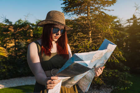 young woman tourist consulting on the map for the travel route, in the hardin of the resort. Concept trip and leisure.の写真素材