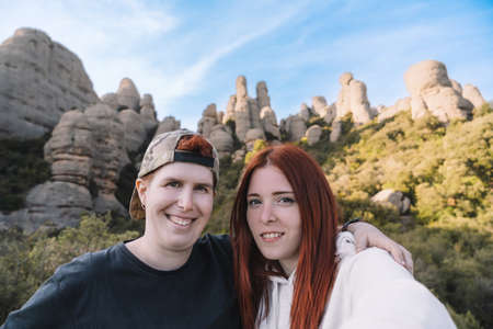 two young men and hikers, taking a selfie from the top of the mountain with their smartphone. Monserrat Spainの写真素材