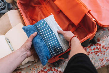 close-up shot of packing a suitcase for a summer holiday. a womans hands organising a luggage...