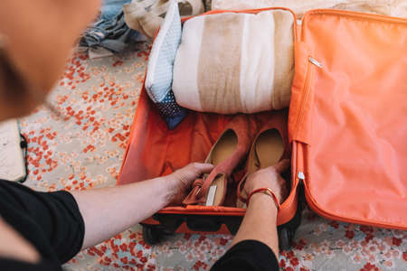 close-up of a suitcase being packed for a summer holiday. a womans hands placing shoes in her luggage. travel and holiday conceptの写真素材