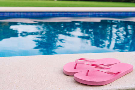 Pink flip flops for pool or beach on grass with pool bottom. Pool water texture. to use text. summer objects.の写真素材