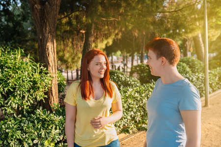 two great friends chatting and strolling happily, in a public park in the city at dawn. young girls enjoying the summer outdoors. concept of friendship and companionship.の写真素材