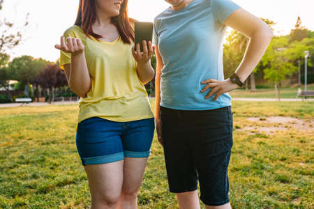 croppet shot of two best friends watching videos on their smartphones in a public park at sunset. young girls enjoying the summer outdoors. concept of friendship and companionship.の写真素材