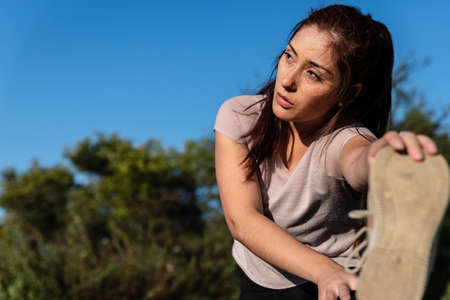 beautiful caucasian young woman doing sports and stretching outdoors in the park