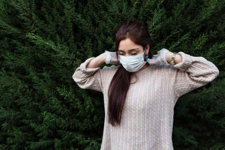 young woman wearing antibacterial mask and latex gloves outdoors as disease prevention and covid-19 and adjusting antibacterial maskの写真素材