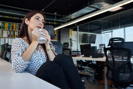 young, beautiful and empowered female entrepreneur, having a coffee break from work, business concept, technology and womanの写真素材