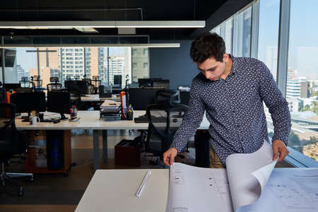 young and active businessman architect and engineer, working in the office and his architectural drawings and plans, business concept, design and manの写真素材