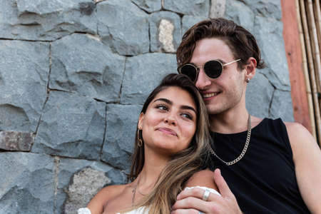young caucasian couple in love sitting down playing, laughing and sharing outdoors in nature,...