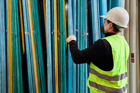 young man wearing a mask in the middle of his job as a construction tool salesman, in the midst of covid 19 pandemic in the new normalityの写真素材
