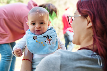 portrait of newborn baby looking towards the camera held by mother in the middle of nature, vacation concept with a newborn babyの写真素材