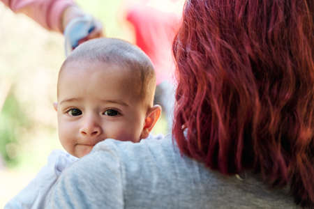 portrait of newborn baby looking towards the camera in the middle of his family, concept of baby in nature.の写真素材