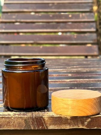 The natural soy candle in dark glass jar and wooden lid next to itの写真素材