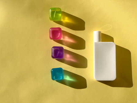 Cosmetic white bottle and coloured transparent ice cubes. Coloured shadowsの写真素材