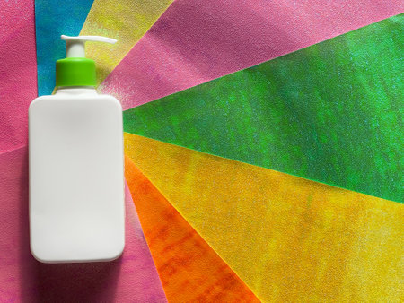 White flat cosmetic bottle with dispenser lies on colorful stripesの写真素材
