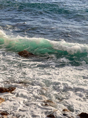 Transparent bright turquoise wave during light storm at sea