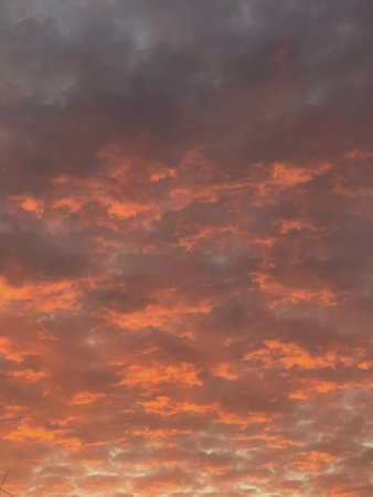 Vivid orange and red clouds during a dramatic sunset over the horizon