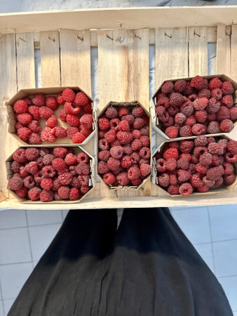 Freshly picked raspberries in wooden crates at market
