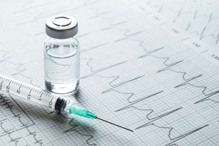 medical ampules and syringe on EKG graph backgroundの写真素材