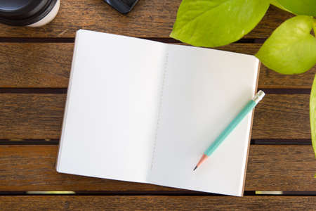 Notebooks, pencils, coffee cups on a wooden tableの写真素材