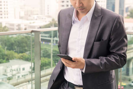 Business man holding the phone The background is a cityの写真素材