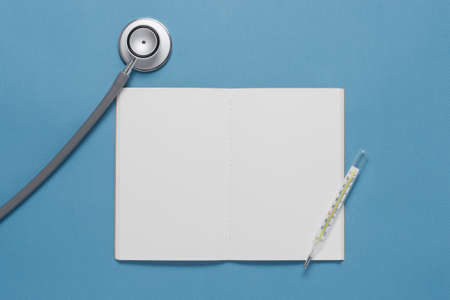 Notebook stethoscope and thermometer on blue backgroundの写真素材