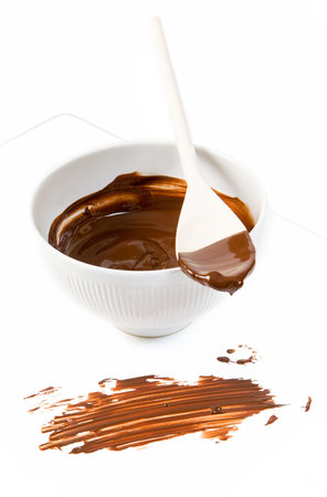 Melted dark chocolate dripping from the wooden spoonの写真素材