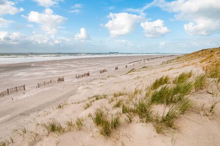 The beach and North Sea on a stormy but sunny day at the Maaslvakte near Rotterdam in the Netherlands. Ships arriving at the Port of Rotterdam in the distance.の写真素材